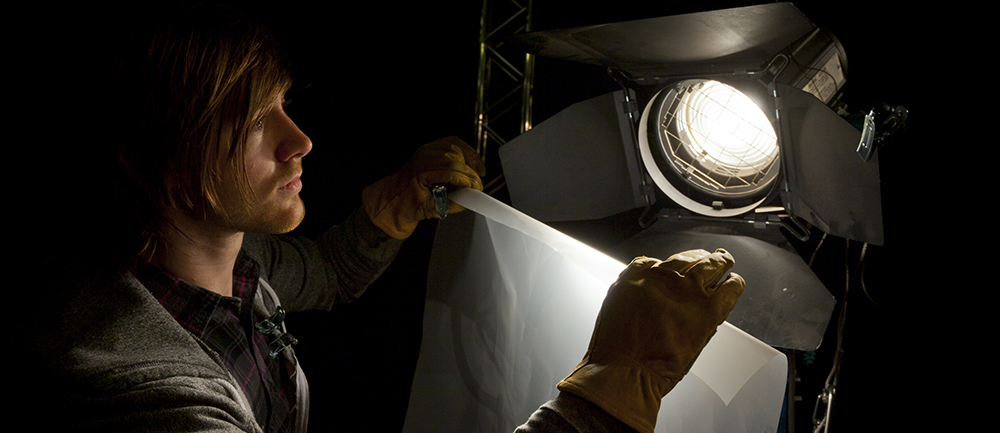Lighting man placing a sheet of diffuser on a studio light in a Television studio; Shutterstock ID 127288280