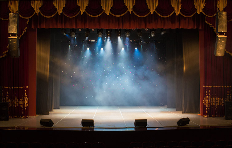 An empty stage with lights shining down through a subtle fog