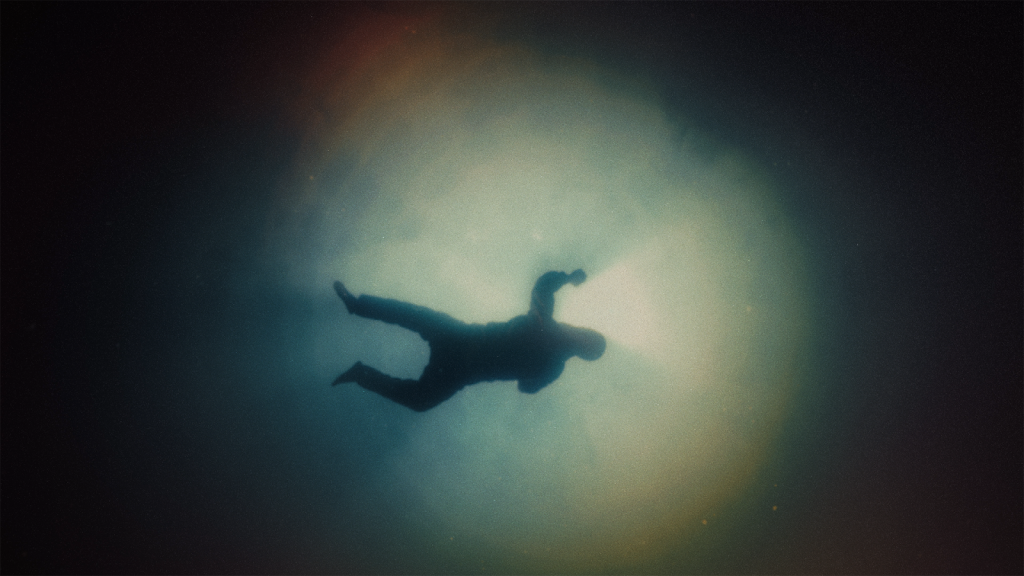 An underwater view of a man floating on the surface illuminated by the sun