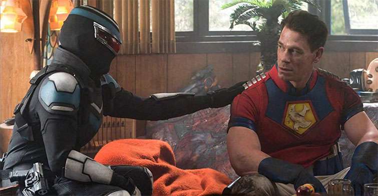 Two characters from the series Peacemaker argue at a table