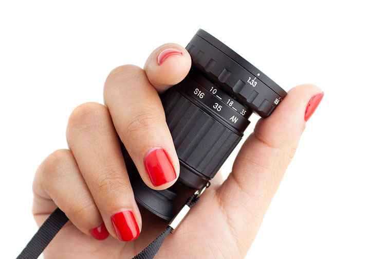 Woman's hand with red painted fingernails holing a collapsed Pocket Mini Director's Viewfinder against a white background