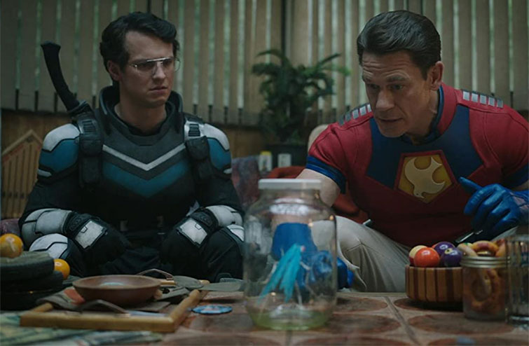 Scene from Peacemaker with two actors discussing at a table