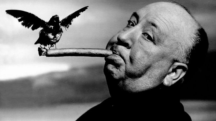Director Alfred Hitchcock smoking a cigar with a black bird at the end of cigar