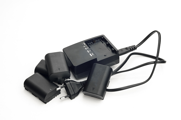 Generic Black Camera Batteries and Charger Against a White Backdrop