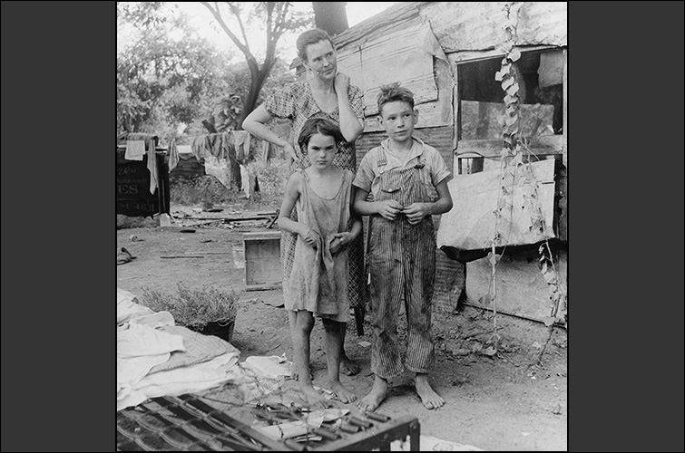 A black-and-white photo of a woman and two children living in poverty during the Great Depression