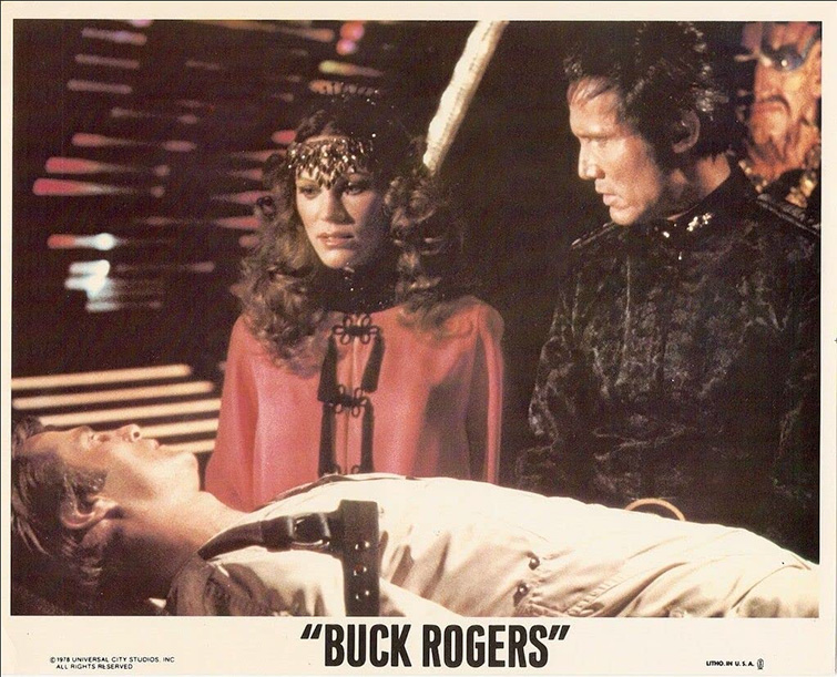 Buck Rogers film still showing Kane and Princess Ardala standing over Rogers on a medical cot