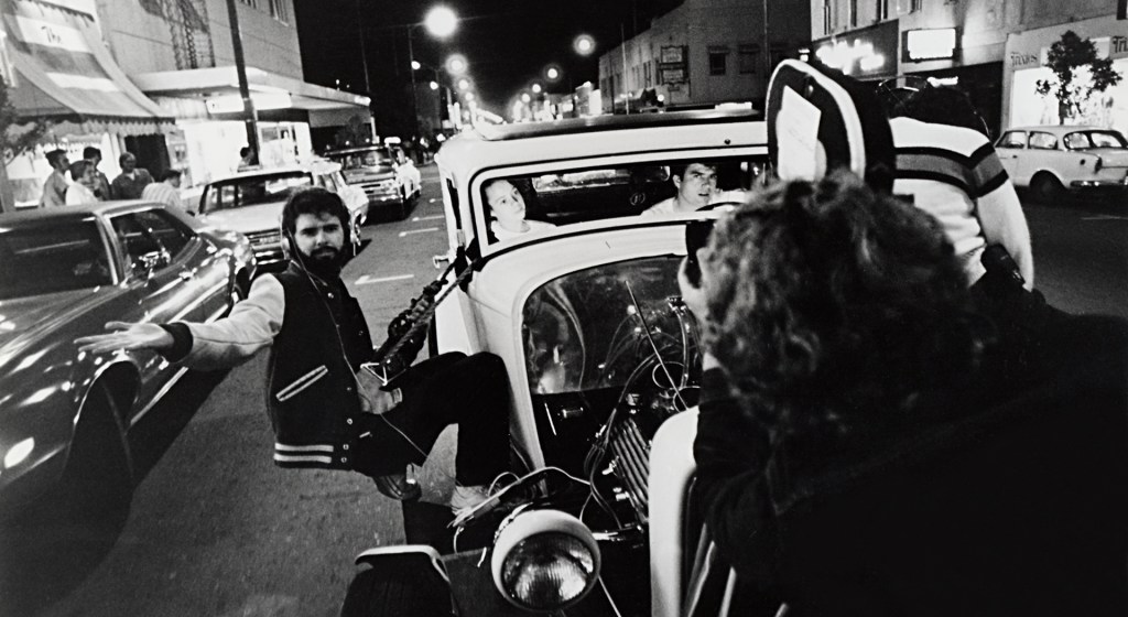 Black and white image of George Lucas on the set of American Graffiti