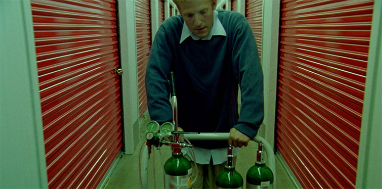 Screen grab from Primer showing the main character pushing a cart through a storage facility