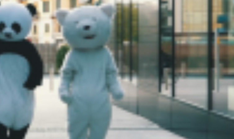Screenshot of a blurry image featuring two people in bear costumes walking down the street