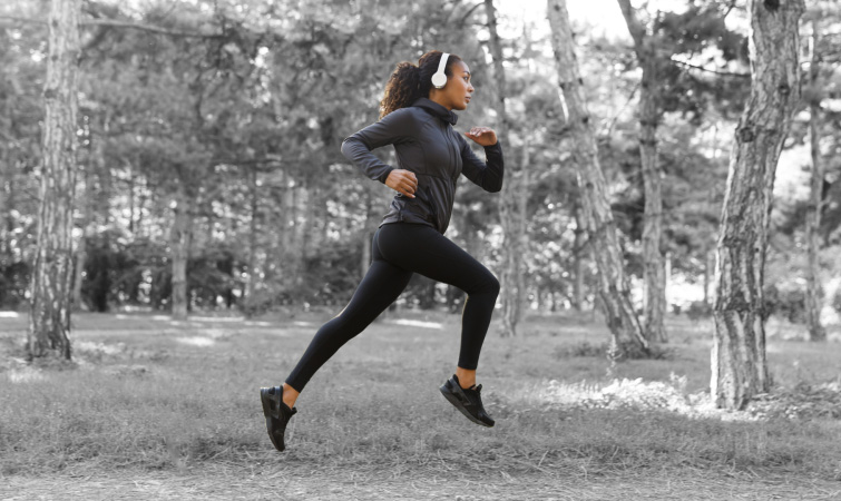 Female athlete running through the park with with background in black and white